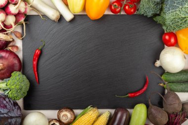 Organik gıda çerçevesi. Ev bahçesinden taze çiğ sebzeler. Kara tahtada. Sağlıklı yemek, diyet konsepti. Mesaj için yer var. en üstteki görünüm.