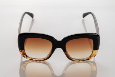 Beyaz yansıtıcı yüzeyde güneş gözlüğü. Modaya uygun, şık aksesuarlar. Tatil ya da yaz konsepti olarak kullan. Parlak güneş ışığına karşı göz koruması.