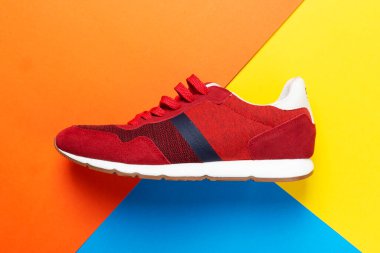 Renkli bir arka planda bir çift spor ayakkabısı. Çok renkli arka planda yeni spor ayakkabılar, kopyalama alanı. Sıradan moda spor ayakkabıları kırmızı renkler. Biçim konsepti.