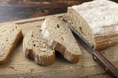 Taze ekmek dilimi ve kırsal masada bıçak kesme.