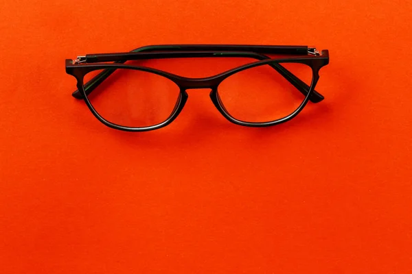 Stylish glasses for vision on an orange background. Fashion accessory. Ophthalmology theme. Space for text.