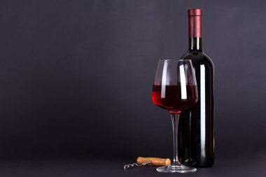 Sealed bottle of red wine, a glass and a corkscrew on a lilac background.With space for text. Wine tasting and drinking culture concept. Alcoholic beverage