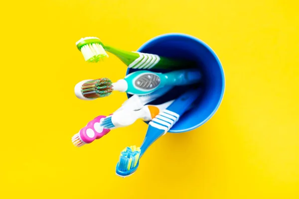 黄色の背景にカップの歯ブラシ 健康管理歯科衛生学 テキスト用のスペース トップ表示 — ストック写真