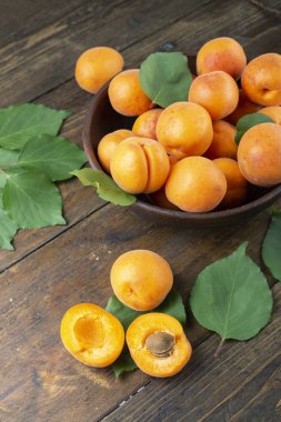 Masanın üzerindeki kil kasede leziz olgun kayısılar. Sağlıklı meyve.