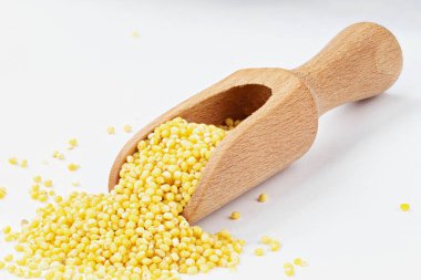 Millet, kaynamış lapa yapmak için beyaz arka planda ahşap bir kepçe..