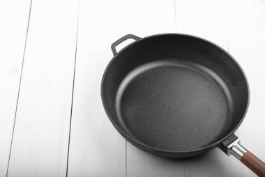 Beyaz ahşap arka planda siyah tava..