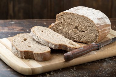 Taze ekmek dilimi ve kırsal masada bıçak kesme.