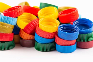 Beyaz arka planda bir sürü renkli plastik şişe kapağı. Geri dönüşüm kavramı.