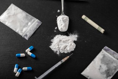 Siyah arka planda kokain ve diğer uyuşturucular, yakın plan. Uyuşturucu kullanımı için sarılmış bir dolar. Yasak uyuşturucular.