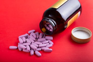 Oval pembe haplar parlak kırmızı arka plandaki bir kavanozdan dökülür. tex için boşluk