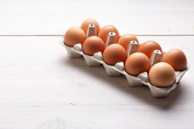 Karton pakette taze organik tavuk yumurtası ya da beyaz ahşap arka planda yumurta kabı. Metin için boşluk.
