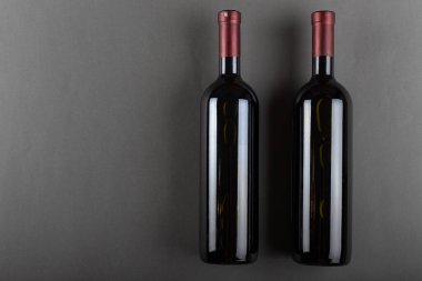 Gri arka planda tıpalanmış kırmızı şarap şişesi. Alkolik içki. Şarap yapımı konsepti.