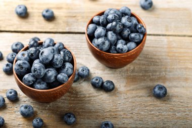 Kil kasede taze yaban mersini ve ahşap bir masaya serpilmiş. Antioksidan içeren yiyecekler. Sağlıklı beslenme.
