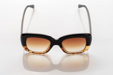 Beyaz yansıtıcı yüzeyde güneş gözlüğü. Modaya uygun, şık aksesuarlar. Tatil ya da yaz konsepti olarak kullan. Parlak güneş ışığına karşı göz koruması.