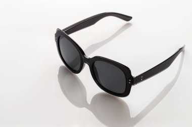 Beyaz yansıtıcı yüzeyde güneş gözlüğü. Modaya uygun, şık aksesuarlar. Tatil ya da yaz konsepti olarak kullan. Parlak güneş ışığına karşı göz koruması.