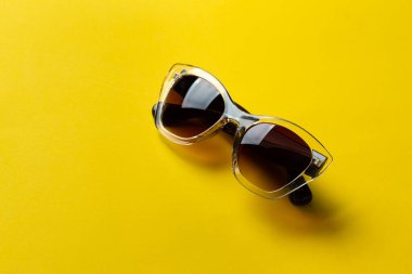 Sarı arka planda güneş gözlüğü. Ultraviyole koruma. Modaya uygun aksesuarlar..