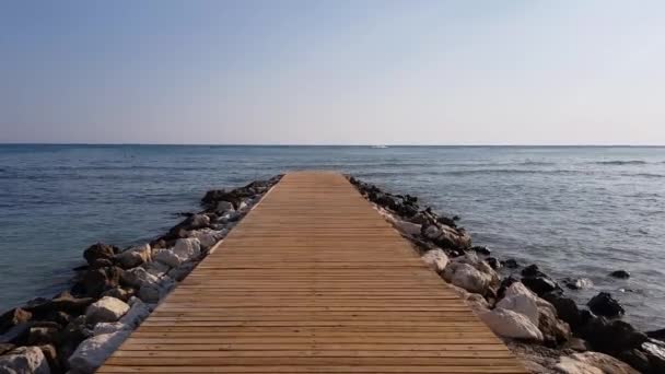 Wooden pier reinforced with stones. Calm sea and blue sky. Tourist season. — Stock Video