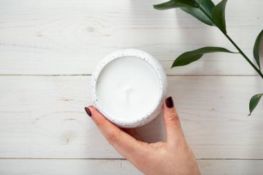 Kadın eli kokulu mum tutuyor, üst manzara. Sonraki için boşluk.