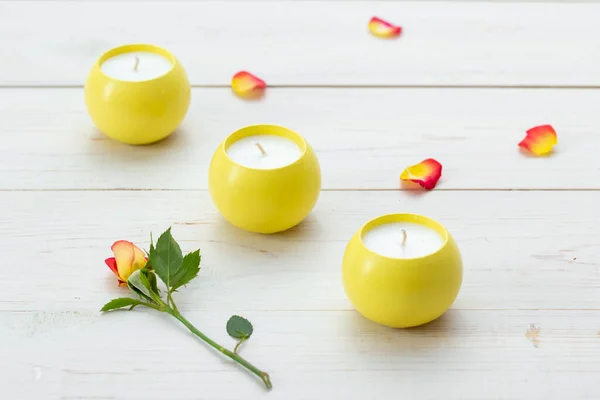 Trzy Żółte Świece Zapachowe Drewnianym Stole Płatki Róż Rozrzucone Powierzchni — Zdjęcie stockowe