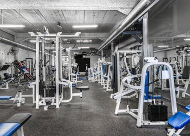 Klasik parlak spor salonu manzarası. Beyaz spor malzemeleri ve mavi koltuklar. Ağırlığı farklı olan halterler