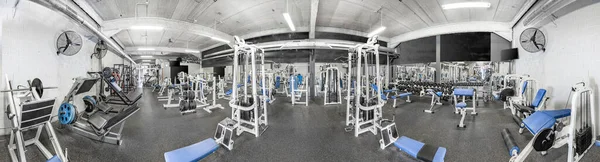 Panorama of a retro bright gym. White sport equipment and blue seats. Barbells of different weight on rack