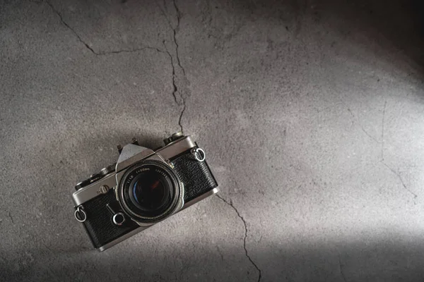 Flat lay of a old film retro camera with shallow depth of field on a stone background. Camera technology concept with a vintage look with copy space.