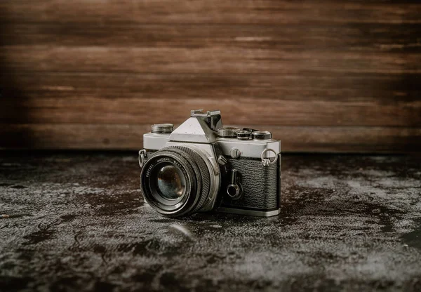 Dark product photography of a old film retro camera with shallow depth of field on a stone background. Camera technology concept with a vintage look with copy space.