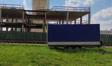 Kapalı araba römorku. Kargo karavanı. Satış, kiralama ve römorkların bakımı. İnşaat alanının arka planı, tren yolu....