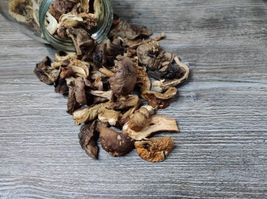 Kavanozun dokulu gri yüzeyinde kurutulmuş domuz mantarı. Cam bir kavanozda kurutulmuş mantar deposu.