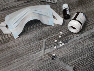 Tıbbi maske, haplar, gri ahşap arka planda şırınga. Tıbbi Düzen