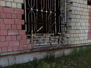 Penceresinde ızgara olan bitmemiş bir evin taş duvarı..