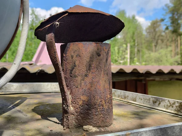 Old rusty chimney on the roof. Iron chimney with an umbrella. The concept of old chimneys from the stove.