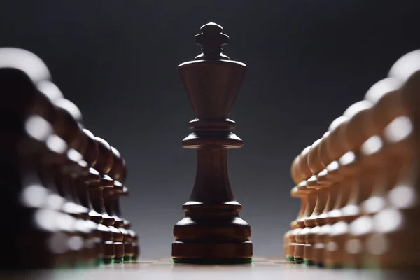 two rows of pawns with black king in the center. Classic Wooden Tournament chess set on black background.