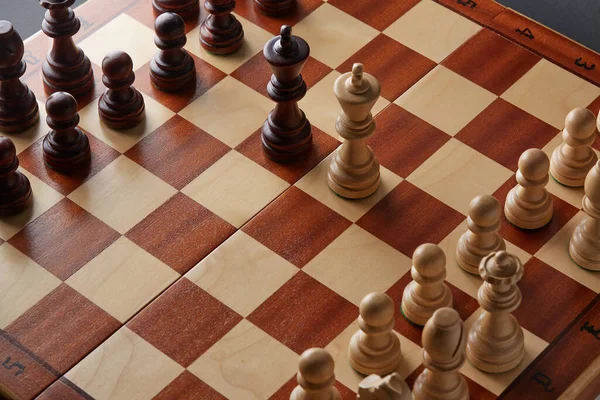 Classic Wooden Tournament chess set on black background. Two kings in centre of board other pieces lined up