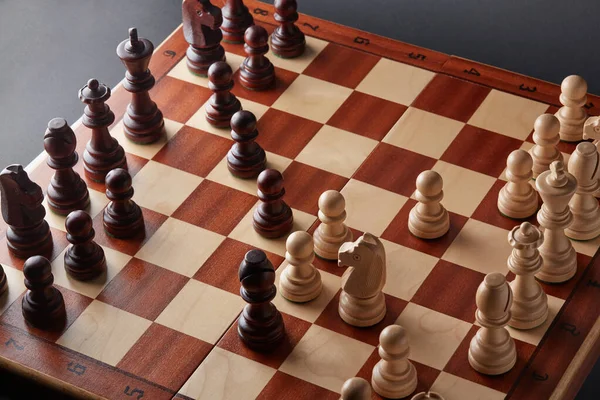 经典的木制锦标赛棋盘设置在黑色背景 棋盘的碎片 这些棋子的排列源于一个叫做女王游戏的开口 — 图库照片