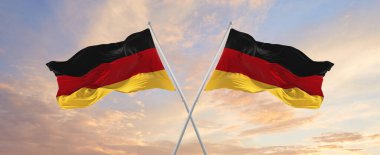 Almanya ve Almanya Federal Cumhuriyeti bayrakları güneşli bir günde gökyüzüne karşı bayrak direkleri sallıyor. İki ülke arasındaki ilişkiyi, diyaloğu sembolize ediyor. 3d illüstrasyon