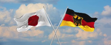 Japonya ve Almanya 'nın bayrakları güneşli bir günde gökyüzüne doğru bayrak direkleri sallıyor. İki ülke arasındaki ilişkiyi, diyaloğu sembolize ediyor. 3d illüstrasyon