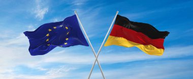 Avrupa Birliği ve Almanya Federal Cumhuriyeti bayrakları güneşli bir günde gökyüzüne karşı bayrak direkleri sallıyor. İki ülke arasındaki ilişkiyi, diyaloğu sembolize ediyor. 3d illüstrasyon