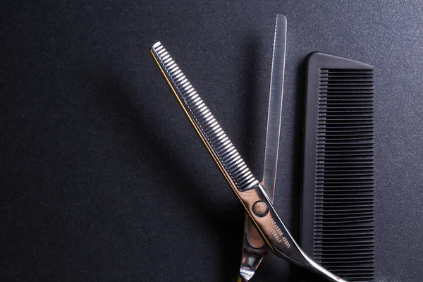 japanese professional hairdressers thinning scissors and comb on black background. Beauty salon equipment. Stylish Professional Barber, Haircut accessories