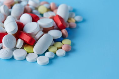 Mavi arka planda izole edilmiş renkli ilaç çeşitleri.