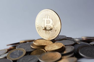 Çeşitli dünya para birimlerinin üzerinde altın ve parlak bitcoin paralar farklı ödeme ve yatırım seçeneklerini temsil eder.