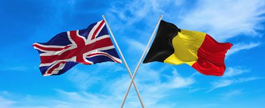 Büyük Britanya ve Belçika 'nın bayrakları rüzgarda dalgalanırken bayrak direkleri gökyüzüne karşı güneşli bir günde bulutlarla. İki ülke arasındaki ilişkiyi, diyaloğu sembolize ediyor. 3d illüstrasyon,