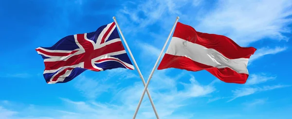 在阳光明媚的日子 大不列颠和奥地利的国旗在风中飘扬 旗杆迎着天空飘扬 象征两国关系 两国间的对话 3D说明 — 图库照片