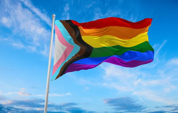 Bulutlu gökyüzünde rüzgarda dalgalanan LGBTQ gökkuşağı bayrağı. Özgürlük ve aşk kavramı. Gurur ayı. Eylemcilik, toplum ve özgürlük kavramı. Uzayı kopyala 3d illüstrasyon.