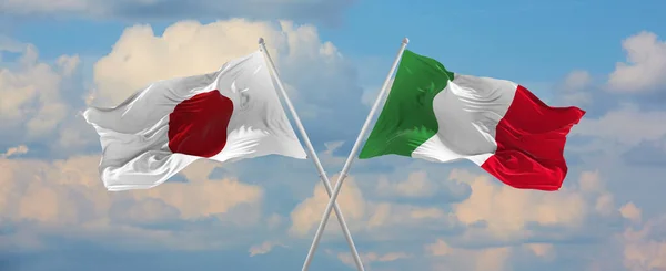 在阳光明媚的日子 日本和意大利的国旗在风中飘扬 旗杆迎着天空飘扬 象征两国关系 两国间的对话 3D说明 — 图库照片
