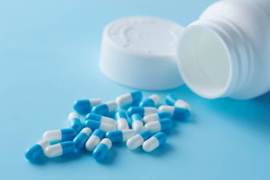 Mavi ve beyaz kapsül hapları mavi arka planda, gölgeli. Küresel sağlık hizmeti kavramı. Antibiyotik ilaç direnci. Antimikrobik kapsül hapları. İlaç endüstrisi.