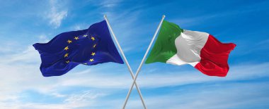 Avrupa Birliği ve İtalya 'nın bayrakları rüzgarda dalgalanırken bayrak direkleri gökyüzüne karşı güneşli bir günde bulutlarla. İki ülke arasındaki ilişkiyi, diyaloğu sembolize ediyor. 3d illüstrasyon,