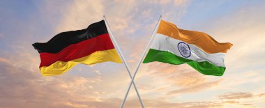 flags of Germany and India  waving in the wind on flagpoles against sky with clouds on sunny day. Symbolizing relationship, dialog between two countries. 3d illustration,