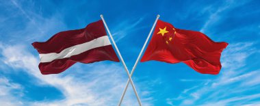 Çin ve Letonya bayrakları rüzgarda dalgalanırken bayrak direkleri gökyüzüne karşı güneşli bir günde bulutlarla. İki ülke arasındaki ilişkiyi, diyaloğu sembolize ediyor. 3d illüstrasyon,