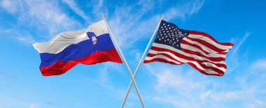 ABD ve Slovenya 'nın bayrakları rüzgarda dalgalanırken bayrak direkleri gökyüzüne karşı güneşli bir günde bulutlarla birlikte. İki ülke arasındaki ilişkiyi, diyaloğu sembolize ediyor. 3d illüstrasyon,